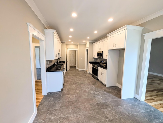 kitchen with sink, white cabinets, backsplash, ornamental molding, and stainless steel appliances