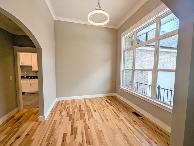 spare room with ornamental molding and light hardwood / wood-style floors