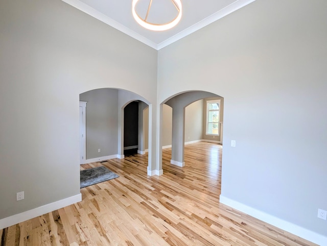 unfurnished living room with crown molding, light hardwood / wood-style floors, and a high ceiling