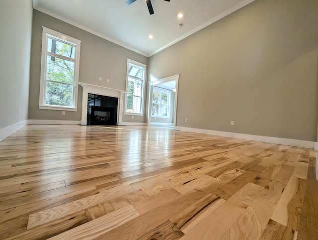 unfurnished living room with ceiling fan, crown molding, light hardwood / wood-style flooring, and a healthy amount of sunlight