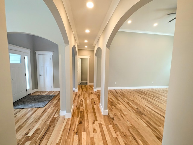 foyer entrance with crown molding, ceiling fan, and light wood-type flooring