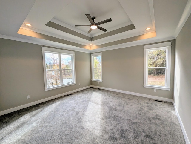 carpeted empty room featuring ornamental molding, ceiling fan, and a tray ceiling