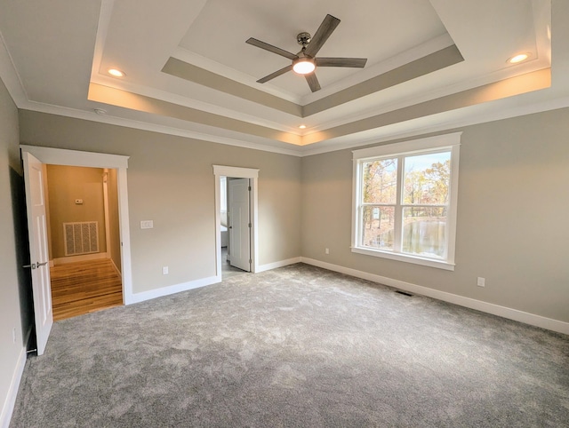 unfurnished bedroom with a tray ceiling, ornamental molding, ceiling fan, and carpet flooring