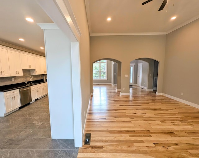 kitchen featuring sink, white cabinetry, tasteful backsplash, stainless steel dishwasher, and ornamental molding