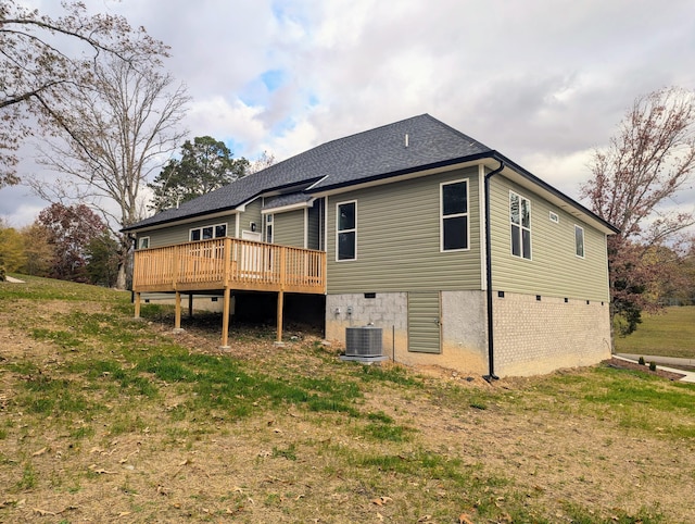 back of property with a wooden deck, a yard, and cooling unit