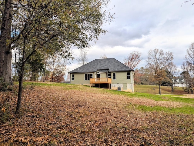 rear view of house featuring a wooden deck and a lawn