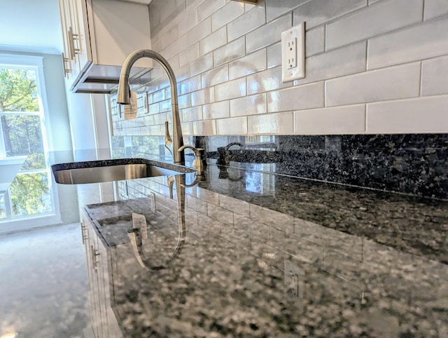 kitchen featuring dark stone counters, sink, and backsplash