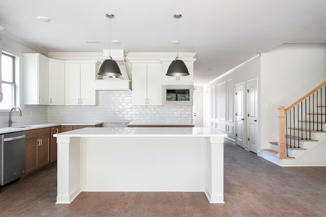 kitchen featuring sink, stainless steel dishwasher, dark hardwood / wood-style floors, pendant lighting, and a kitchen island