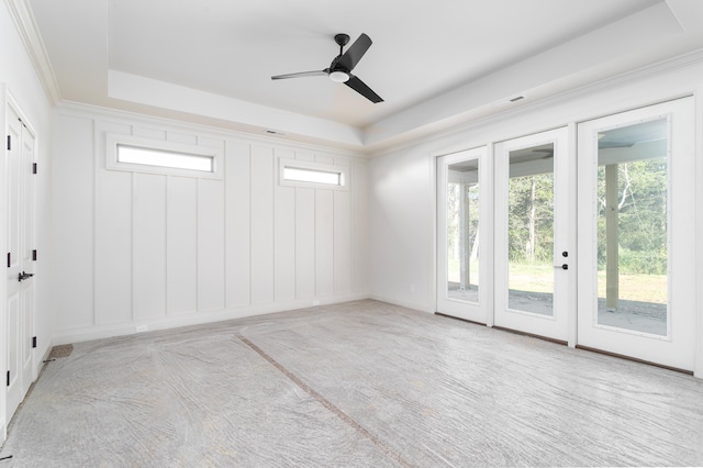 spare room featuring a tray ceiling, light carpet, ceiling fan, and ornamental molding