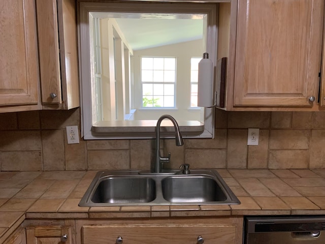 kitchen with tile countertops, stainless steel dishwasher, tasteful backsplash, and sink