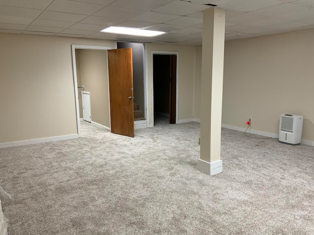 basement featuring a paneled ceiling and light carpet