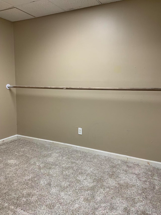 carpeted spare room featuring a drop ceiling