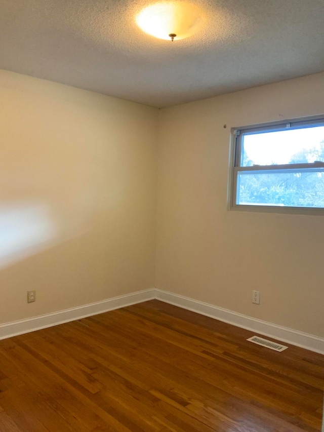 spare room with a textured ceiling and dark hardwood / wood-style flooring