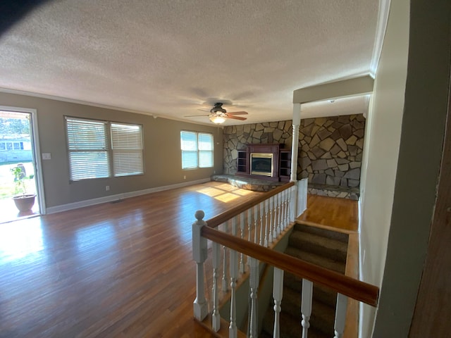 living room with a fireplace, hardwood / wood-style floors, a textured ceiling, and ornamental molding