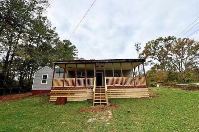 rear view of property featuring a yard and a porch