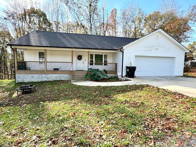 single story home featuring a porch, a garage, and an outdoor fire pit