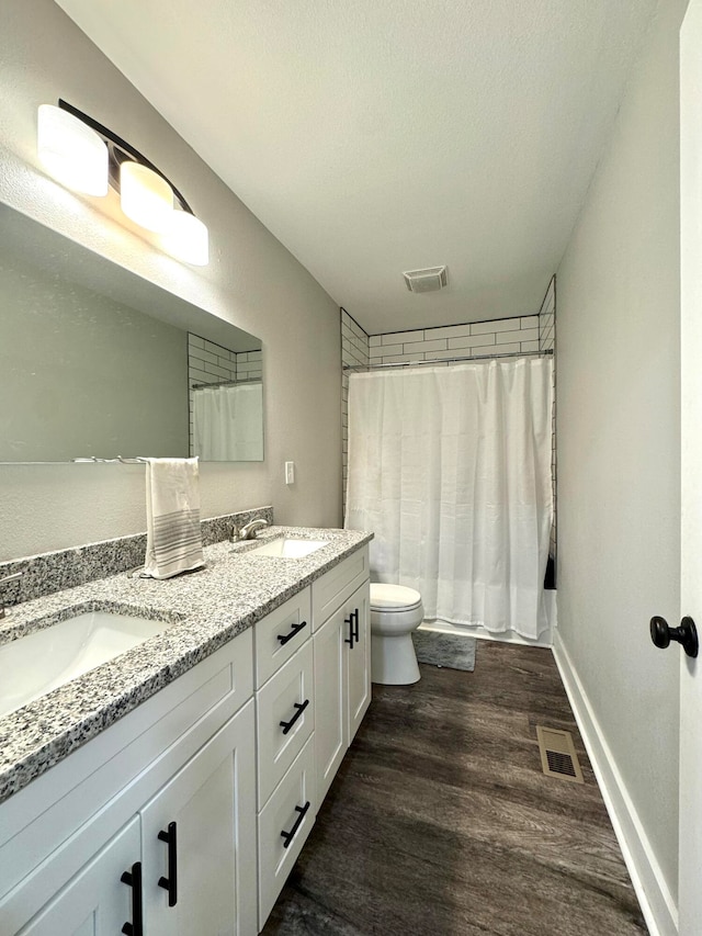 bathroom with wood-type flooring, vanity, a textured ceiling, and toilet