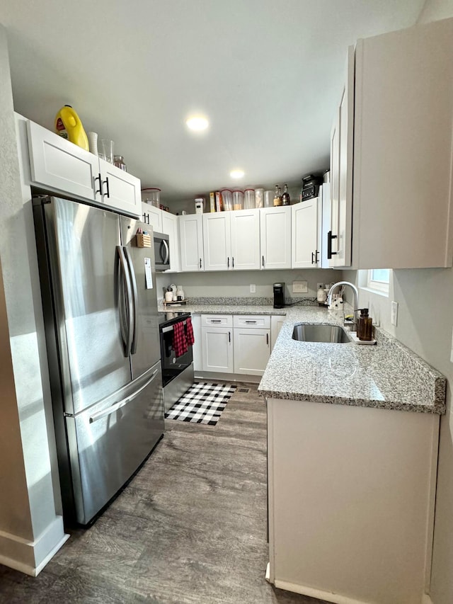 kitchen with white cabinetry, sink, stainless steel appliances, light stone counters, and dark hardwood / wood-style floors