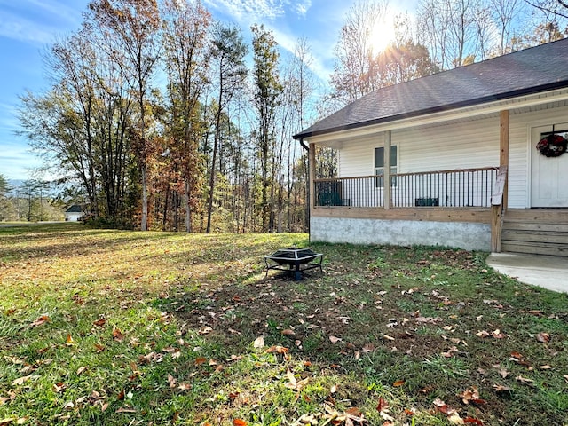 view of yard featuring covered porch and an outdoor fire pit