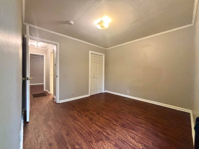 unfurnished bedroom featuring dark hardwood / wood-style floors, ornamental molding, a textured ceiling, and a closet