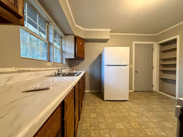 kitchen with white refrigerator, crown molding, and sink