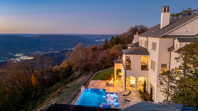 pool at dusk with a patio area and a jacuzzi