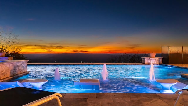 pool at dusk featuring pool water feature