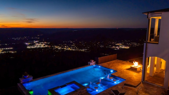 pool at dusk with an in ground hot tub and a fire pit