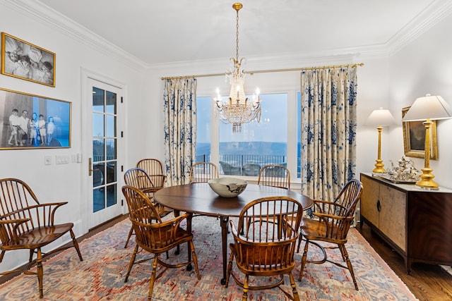 dining space with crown molding, dark wood-type flooring, and an inviting chandelier