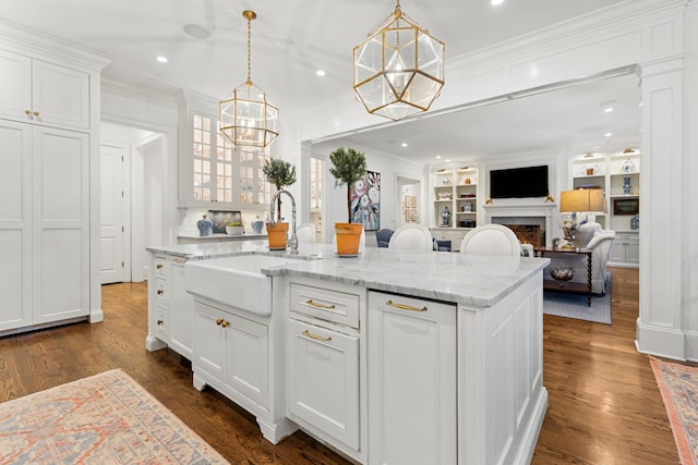 kitchen with crown molding, white cabinetry, dark wood-type flooring, and a kitchen island with sink