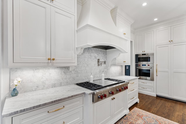 kitchen with custom exhaust hood, backsplash, white cabinets, appliances with stainless steel finishes, and dark hardwood / wood-style flooring