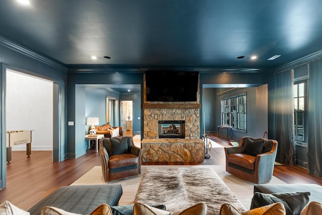 living room featuring a fireplace, light hardwood / wood-style floors, and ornamental molding