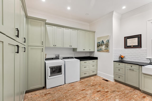 washroom with cabinets, washing machine and dryer, crown molding, and sink