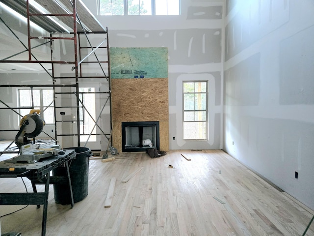 unfurnished living room featuring a high ceiling, wood-type flooring, and a stone fireplace