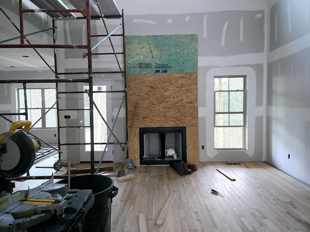 unfurnished living room featuring plenty of natural light, a towering ceiling, and hardwood / wood-style flooring