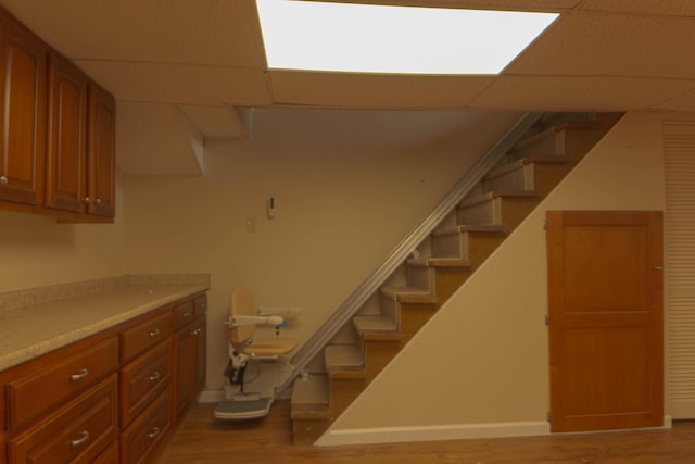 basement featuring a paneled ceiling and light hardwood / wood-style floors