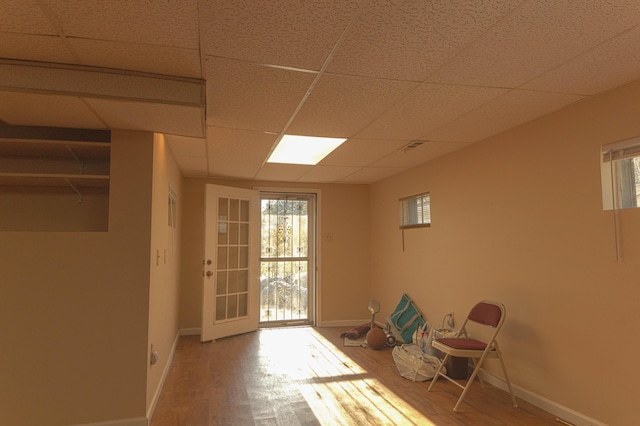 interior space featuring a paneled ceiling, a wealth of natural light, and hardwood / wood-style flooring