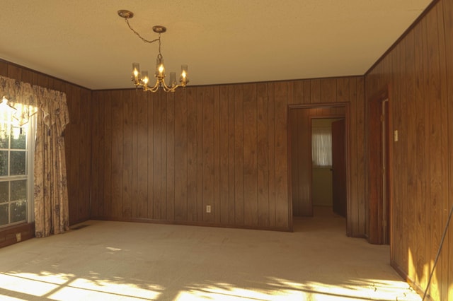 carpeted empty room with wooden walls and an inviting chandelier