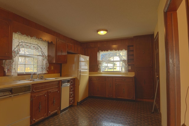 kitchen featuring a textured ceiling, wood walls, sink, and white appliances