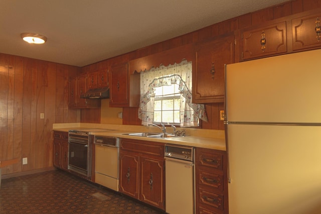 kitchen with wood walls, white appliances, and sink