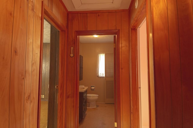 hall with light carpet and wood walls