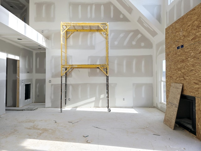 unfurnished living room featuring a healthy amount of sunlight, a fireplace, and a high ceiling