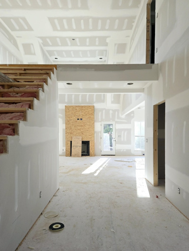 unfurnished living room featuring a fireplace and a high ceiling