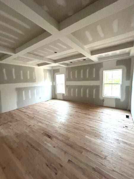 empty room with coffered ceiling and hardwood / wood-style floors