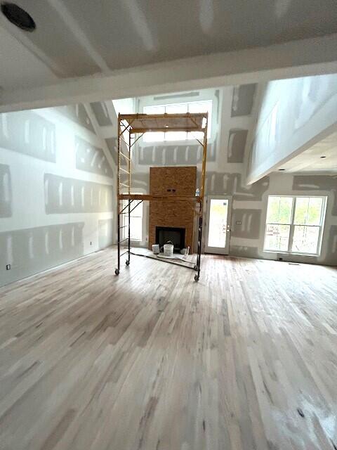 unfurnished living room featuring high vaulted ceiling, wood-type flooring, and a fireplace