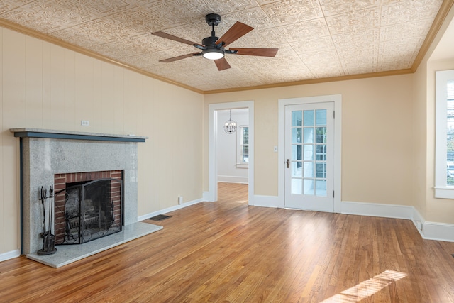 unfurnished living room featuring a fireplace, wood-type flooring, ceiling fan, and ornamental molding