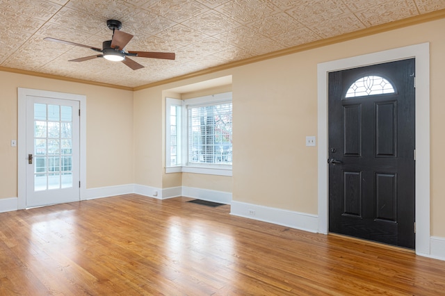 foyer with hardwood / wood-style flooring, a wealth of natural light, ornamental molding, and ceiling fan