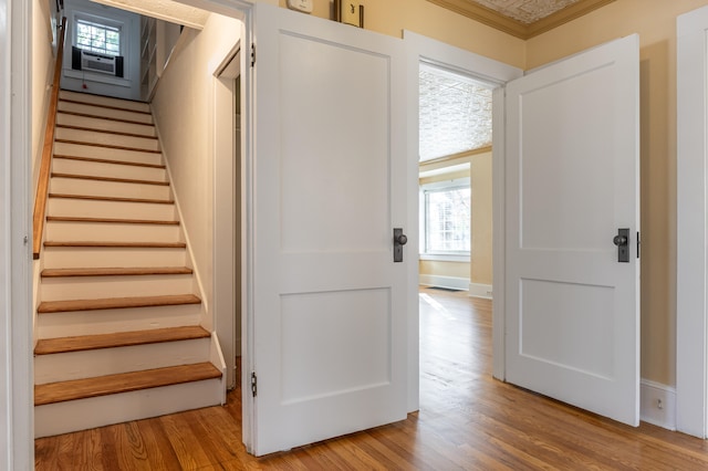 staircase with hardwood / wood-style floors, cooling unit, and ornamental molding