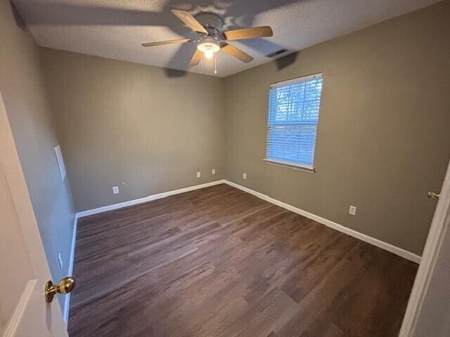 spare room featuring dark hardwood / wood-style floors, ceiling fan, and a textured ceiling