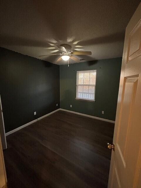 empty room with ceiling fan and dark hardwood / wood-style flooring